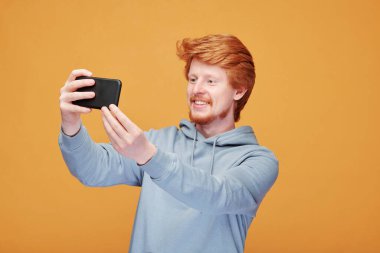 Pozitif kızıl saçlı, sakallı, turuncu arka planda duran ve terfiden bahseden genç bir adam.