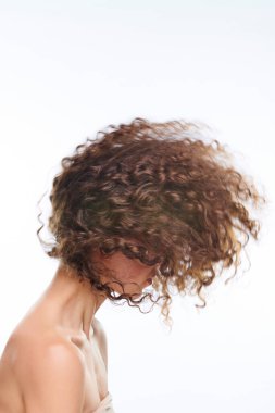 Uzun dalgalı siyah saçları olan, sabah duşundan sonra yüzünü kameranın önüne saklayan genç ve güzel bir kadın.