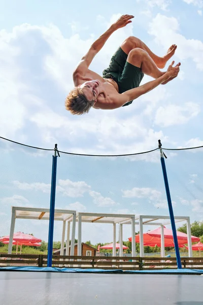 Mladý Topless Sportovec Zelených Kraťasech Skákání Přes Trampolínu Obklopen Sítí — Stock fotografie