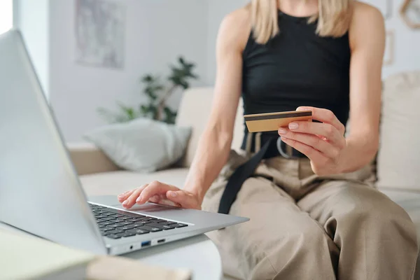 穿着便服的年轻女子手拿着信用卡放在笔记本电脑键盘上 在网上购物时按下按钮 — 图库照片