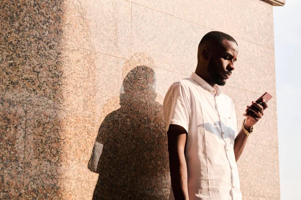 Homem Negro Jovem Concentrado Camisa Branca Parede Livre Leitura Sms — Fotografia de Stock