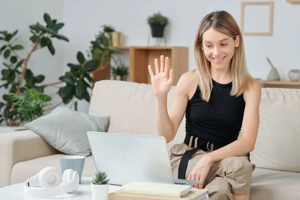 Joven Mujer Sonriente Ropa Casualwear Sentado Sofá Saludando Mano Amigo — Foto de Stock