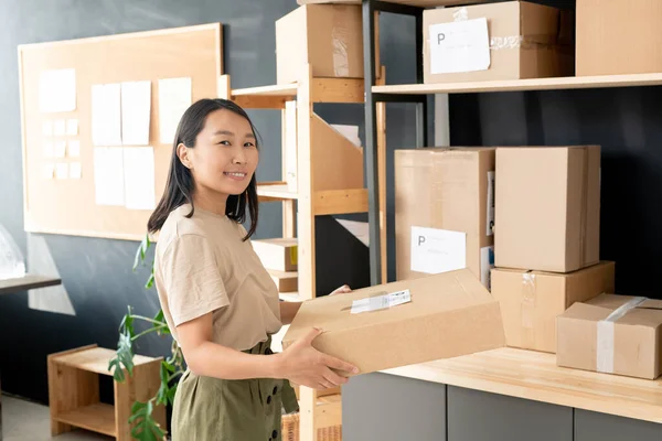 Sonriente Joven Trabajadora Oficina Correos Trastero Llevando Caja Cartón Con — Foto de Stock