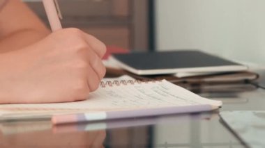 Ödev yapan tanınmayan bir kız öğrenciyi yakından çek. Not defterine yazıyor.