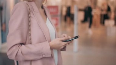 AVM 'de yürürken cep telefonu tutan ve mesajlaşan yavaş yavaş tanınmayan genç bir kadının orta bölüm takibi
