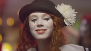 Cadılar Bayramı kostümü giymiş genç bir kadının portresi. Ev partisinde kameraya bakarken gülümseyip dans ediyor.