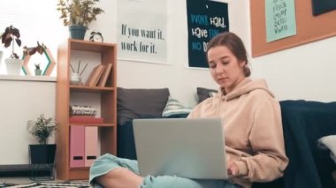 Genç kolej öğrencisinin rahat yurdunda otururken ve dizüstü bilgisayarında daktilo yazarken fotoğrafını çekiyorum.