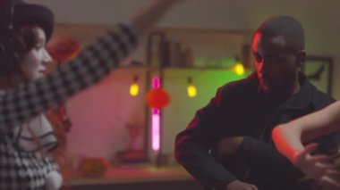 Cadılar Bayramı kostümü giymiş, ev partisinde dans eden genç ve mutlu kadınların el ele tutuşması.