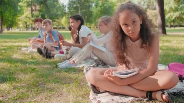 Tracking Portret Schot Van Schoolmeisje Zitten Cross Legged Deken Groen — Stockvideo