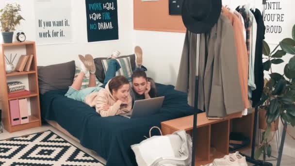 追踪年轻女性朋友躺在舒适的大学宿舍床上 在笔记本电脑上看电影的照片 — 图库视频影像