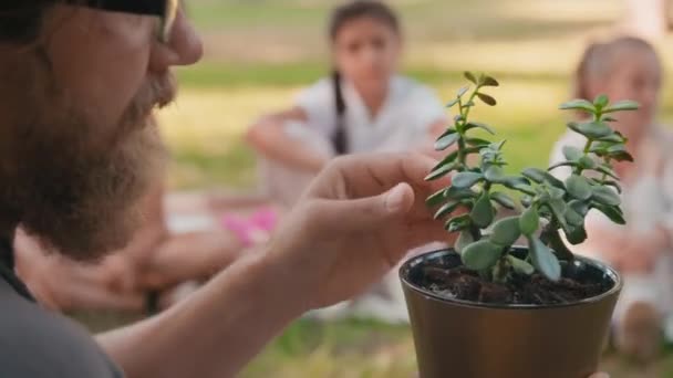 戴眼镜的大胡子男子近照 向好奇的学童展示盆栽 教他们如何在户外照料盆栽 — 图库视频影像
