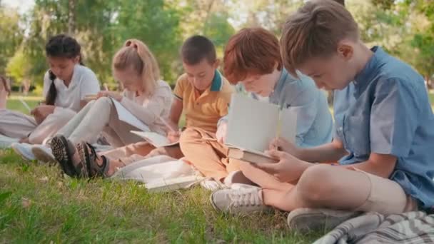 Tracking Shot Cute Schoolchildren Sitting Blankets Green Grass Park Sunny — Vídeo de stock
