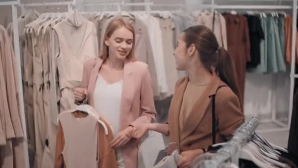 Seguimiento Tiro Mujeres Jóvenes Felices Llevando Ropa Perchas Charlando Mientras — Vídeos de Stock