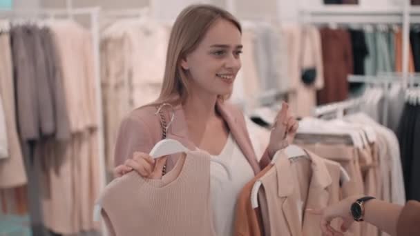 Medium Shot Happy Young Woman Smiling Showing Different Garments Hangers — Stock Video