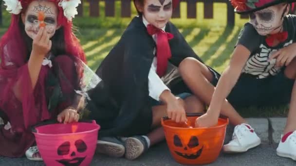 Ujęcie Szczęśliwych Dzieciaków Halloween Kostiumach Siedzących Krawężniku Przedmieściach Dzielących Się — Wideo stockowe