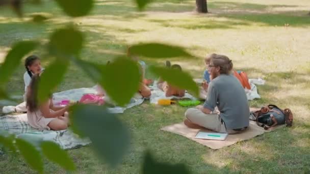 Enseignant et écoliers Déjeuner relaxant et déjeuner dans le parc — Video