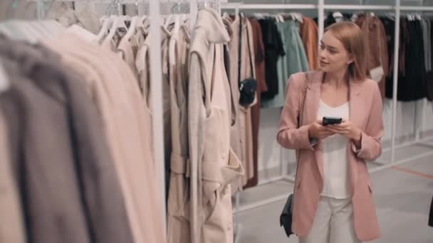 穿着西装的年轻女子在商店购物时拍下衣服价签的中景照片 — 图库视频影像