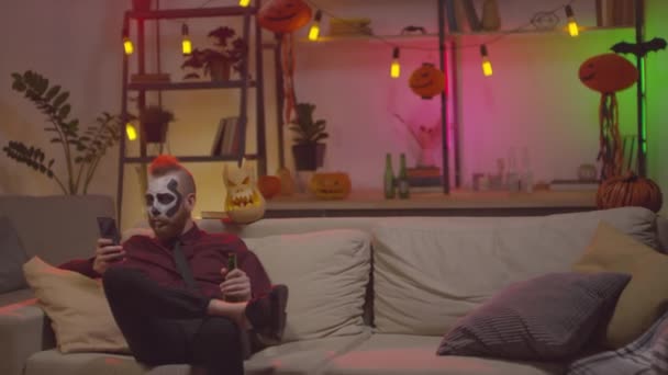 Handheld Shot Człowieka Makijaż Halloween Siedzi Kanapie Przeglądania Internetu Telefon — Wideo stockowe