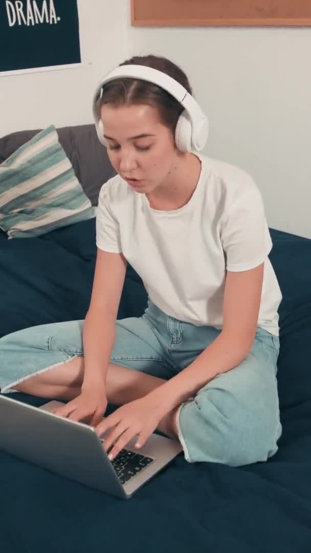 헤드폰을 기숙사 침대에 노트북으로 타자를 하면서 음악을 소녀의 — 비디오