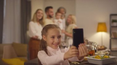 Küçük şirin bir kızın portresi. Ailesinin ve kendisinin fotoğrafını çekiyor. Akıllı telefon kamerasıyla.