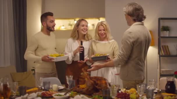 自宅のリビングルームで一緒に感謝祭の夕食のために準備4世代の人々のグループ — ストック動画
