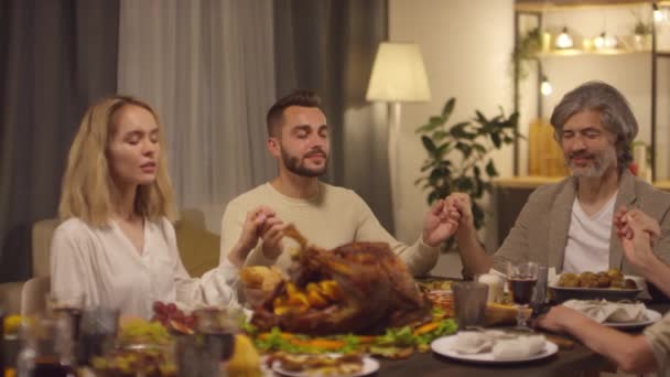 感謝祭の日をお祝いし始め 感謝祭のテーブルに座っている人々の中のショット祈り — ストック動画