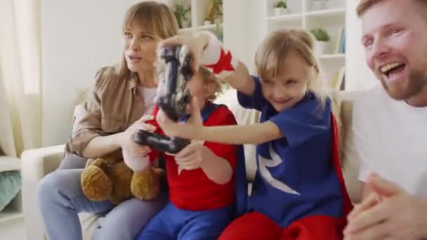 Medelhög Bild Ung Familj Med Två Barn Superhjältedräkter Som Spelar — Stockvideo