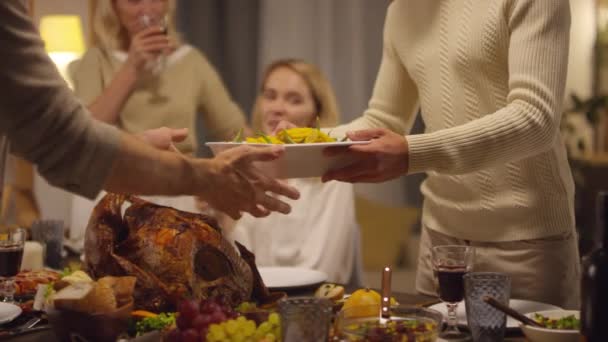 Två Män Dukar Thanksgiving Middagsbord Medan Två Avslappnade Kvinnor Tittar — Stockvideo