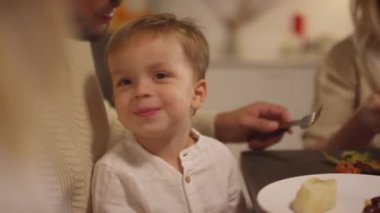 Babasının kucağında oturmuş babasının yemek yerken çekilmiş orta boy portresi.