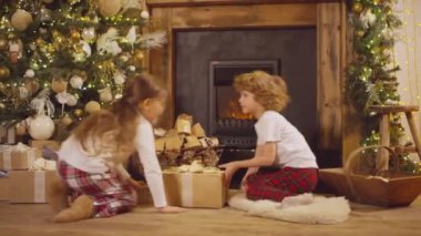 Kırmızı kareli pantolonla Noel hediyelerine koşan küçük çocukların göz hizasında fotoğrafı şöminede sallanıyor ve tahmin ediyor.