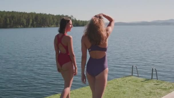 Повільний Середній Знімок Двох Молодих Жінок Купальниках Йдуть Озерному Пірсу — стокове відео