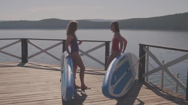 Full Shot Young Women Swimsuits Standing Lake Pier Leaning Sup — Stock Video