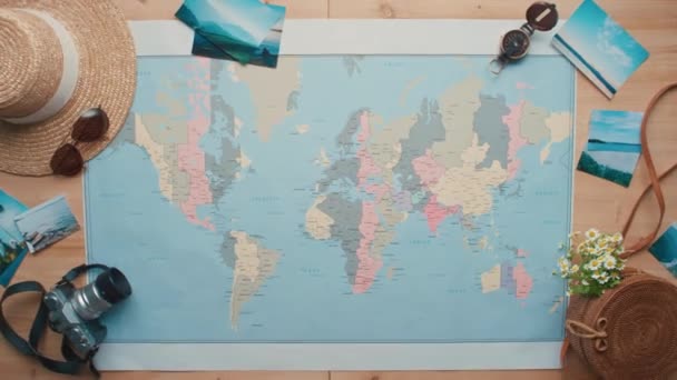 印刷された世界地図上にチケットと2つの国際パスポートを敷設女性の手のフラットレイアウトショットで上記のズームから水平 — ストック動画