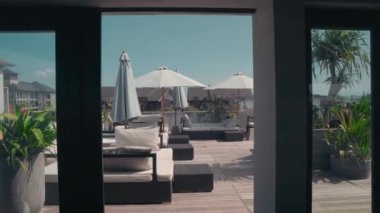 Bali 'nin şatafatlı, şezlonglu, plaj şemsiyeli, yeşillikli ve şehir manzaralı açık teras çekimleri.