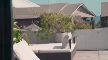 Arka planda villalar olan egzotik bir tatil beldesinde yeşillik sallarken çekilen çekimler.