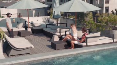 Çekici bir çiftin sandalyeye oturup kokteyl getirdiği yüksek açılı bir çekim.