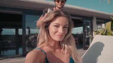 Genç ve çekici bir çiftin kameraya bakıp gülerken ve gülümserken akıllı telefondan görüntülü konuşması.