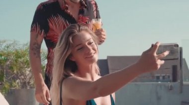 Havuz başında görüntülü konuşma yapan neşeli çiftin orta boy yakın çekimi.