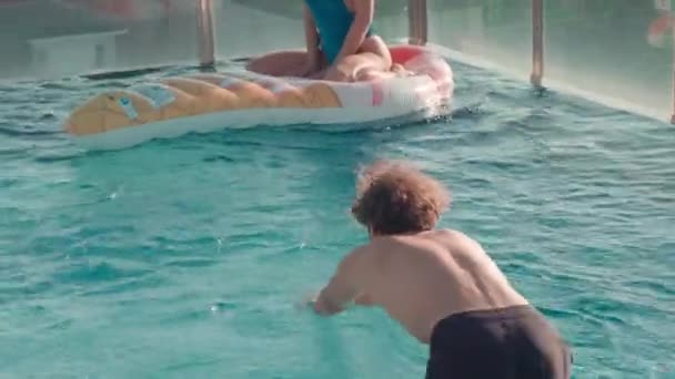 全景美丽的女人坐在冰淇淋水床上看着男朋友在室外露台游泳池里游泳 — 图库视频影像