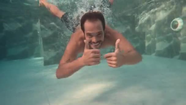 男子在度假跳入游泳池时的水下镜头 对着镜头微笑 — 图库视频影像