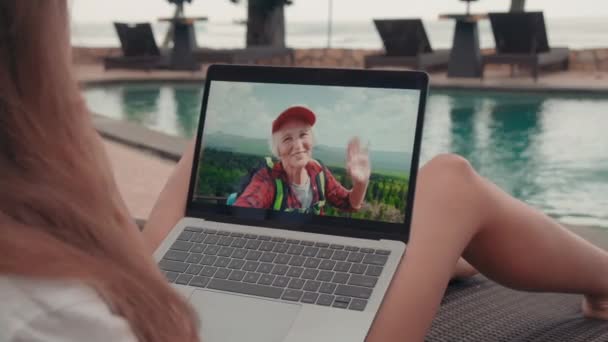 在热带度假胜地的日光浴床上与活跃的运动健美的祖母通过视频向对方致意的情景 — 图库视频影像