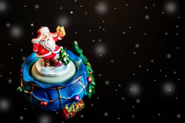 Kar taneleri ile siyah arka plan üzerinde Noel Baba şirin oyuncak izole