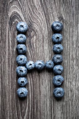 H harfi yaban mersini çilek ahşap arka plan üzerinde dışarı koydu