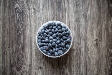 Olgun lezzetli böğürtlen ve çilek bir kabın içinde ahşap bir masa üzerinde