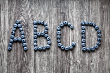 Yaban mersini çilek ahşap arka plan üzerinde dışarı harfi A B C D koydu