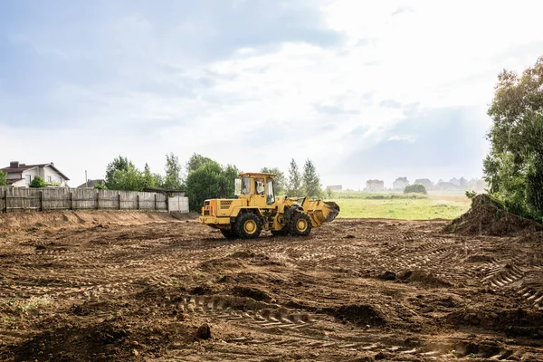 Gran cargador de ruedas amarillo alinea un pedazo de tierra para un nuevo edificio —  Fotos de Stock