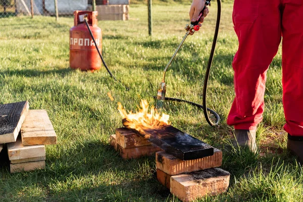 Bir adam eski Japon teknolojisini kullanarak propan ile ahşap plakalar yakar, bir ev inşa etmek için karşı karşıya malzeme oluşturma