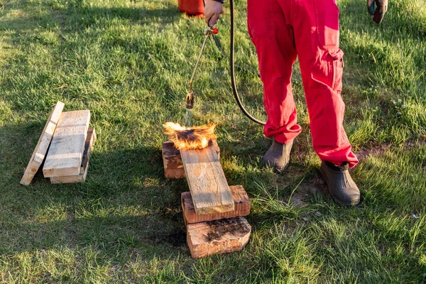 Ένας άνθρωπος καίει ξύλινες σανίδες με προπανίου χρησιμοποιώντας παλιά ιαπωνική τεχνολογία, δημιουργώντας αντιμετωπίζοντας υλικό για την οικοδόμηση ενός σπιτιού — Φωτογραφία Αρχείου