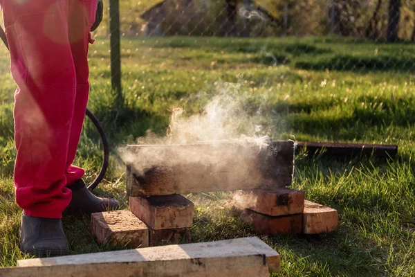 Человек сжигает деревянные доски пропаном по старинной японской технологии, создавая облицовочный материал для строительства дома — стоковое фото
