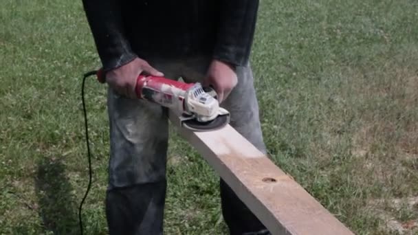 Ein Mann Hält Und Schleift Eine Holzplanke Mit Einem Schleifer — Stockvideo